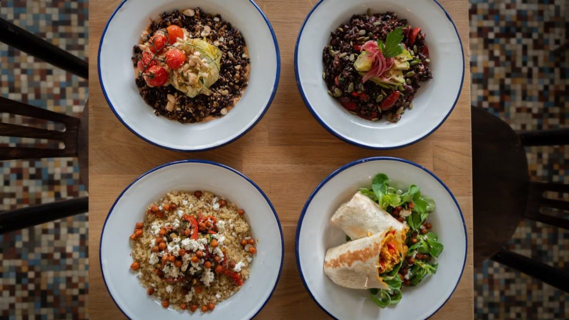 Top view of four healthy grain and vegetable bowls on a wooden table, perfect for nutritious meal ideas.