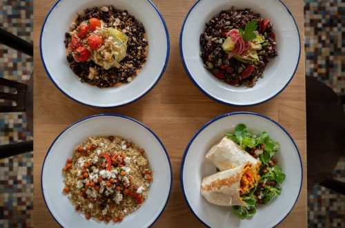 Top view of four healthy grain and vegetable bowls on a wooden table, perfect for nutritious meal ideas.